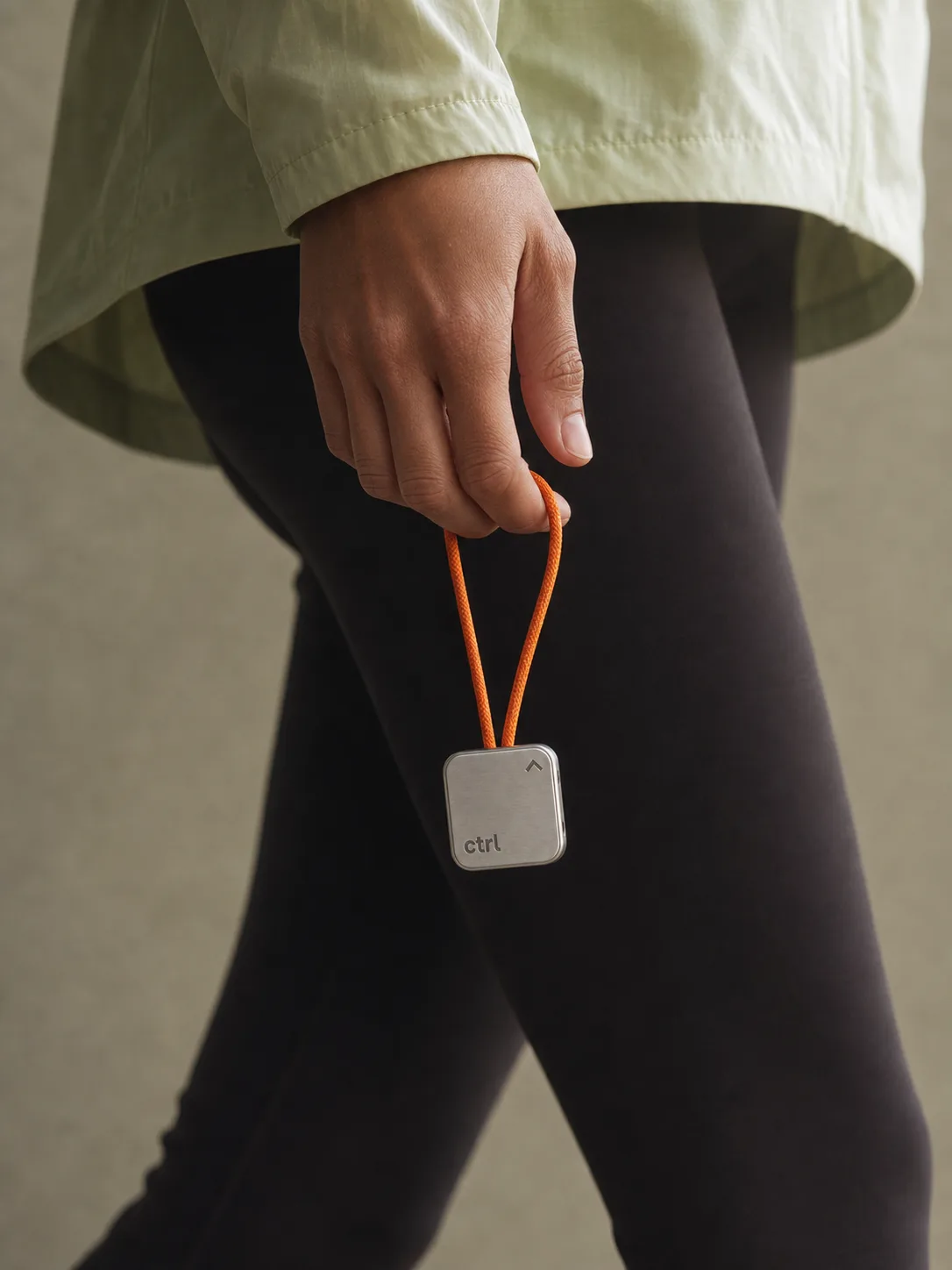 Person walking outside in daylight, carrying the ctrl key on its cord
