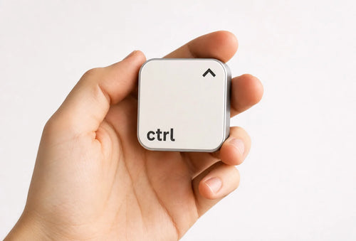 Eine Hand hält den ctrl key vor einem hellen Studiohintergrund