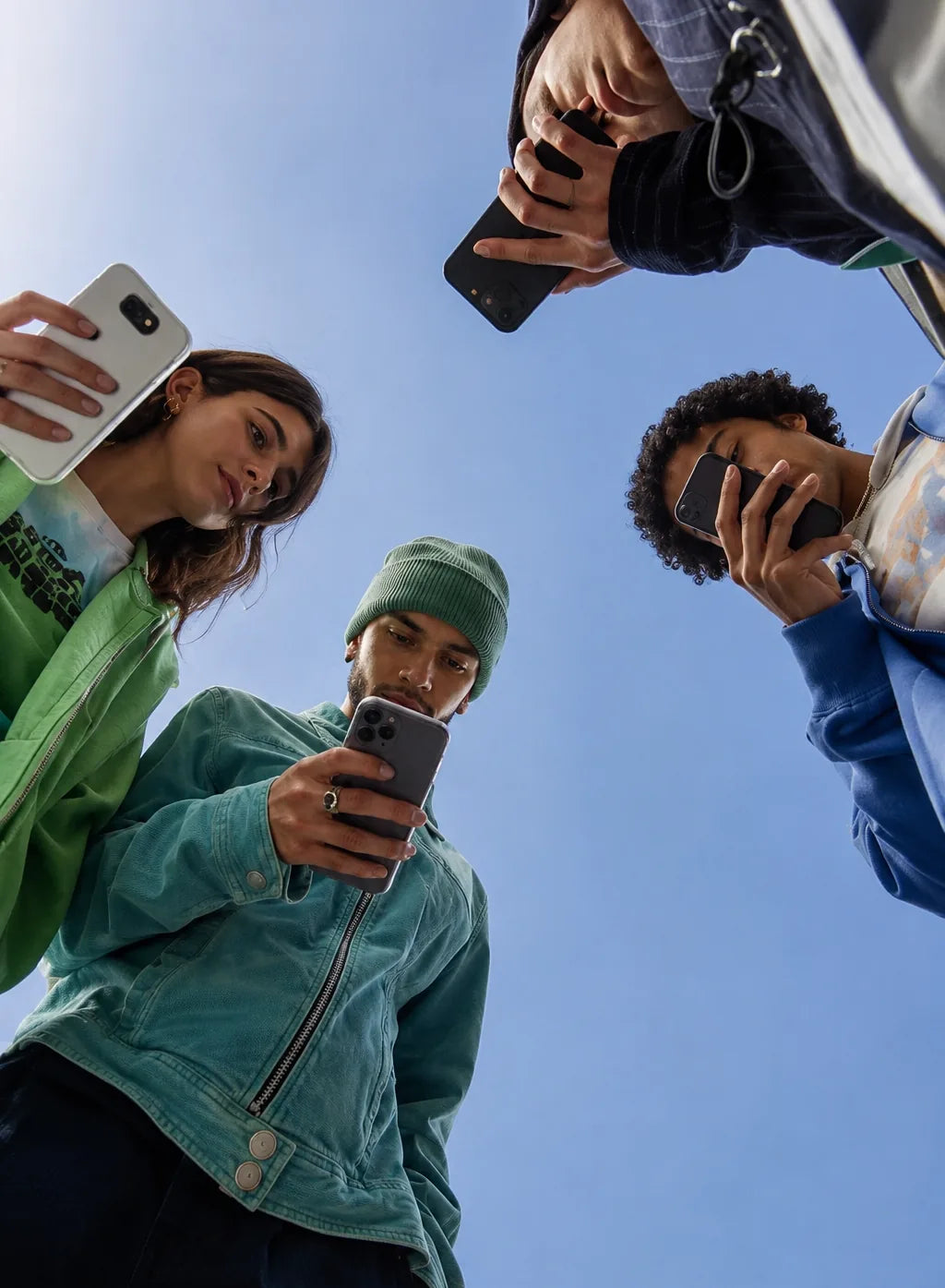 Vier Freunde im Kreis, alle starren aufs Handy