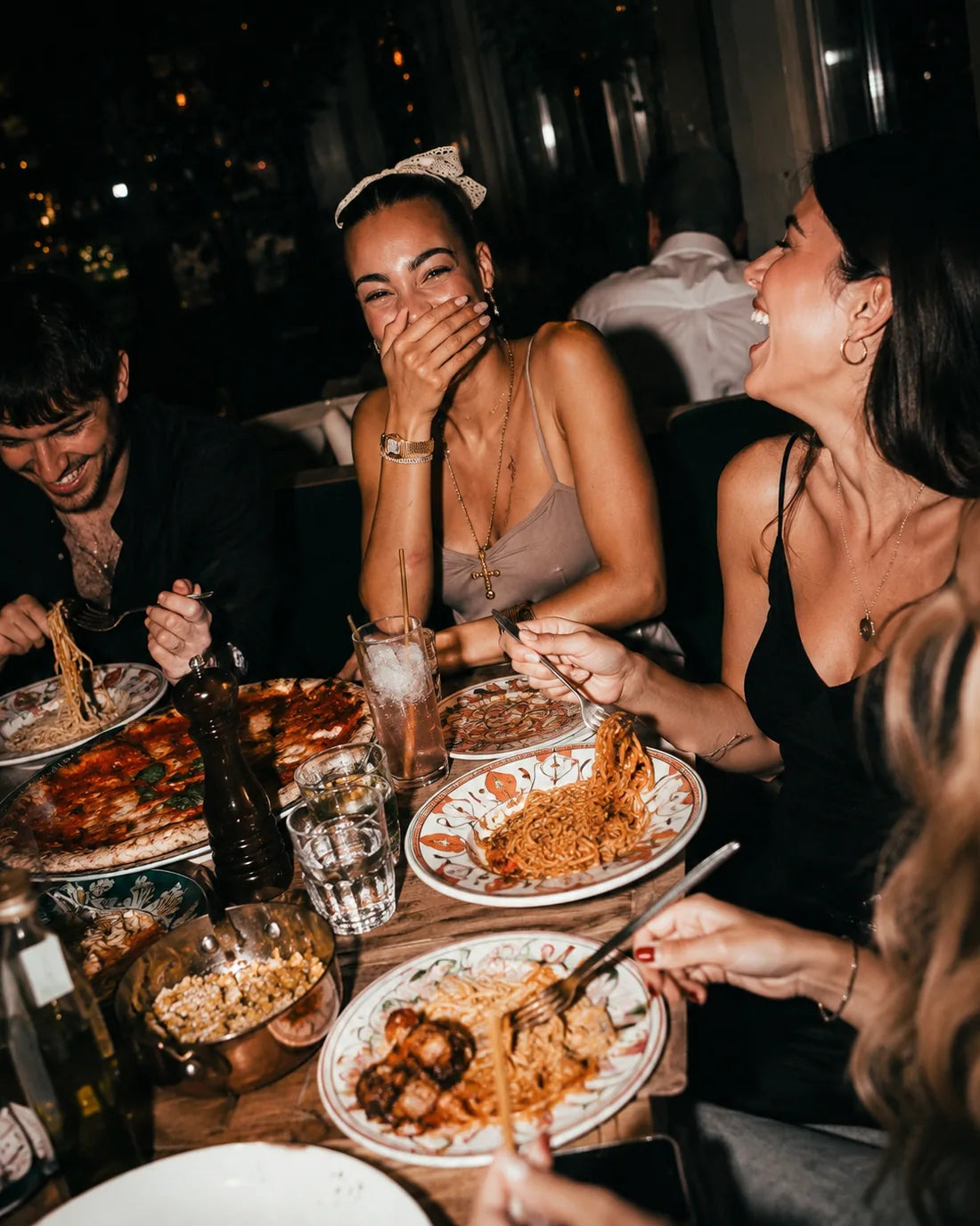 Freunde beim Abendessen, sie lachen über gemeinsamem Essen